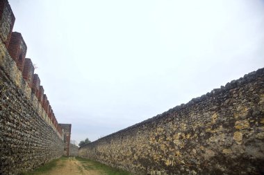Bulutlu bir günde parkta tahkimatla çevrelenmiş toprak yol.