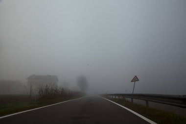 Sonbaharda sisli bir günde bir su akıntısı ile çevrili köy yolu