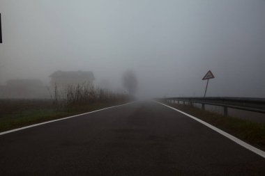Sonbaharda sisli bir günde bir su akıntısı ile çevrili köy yolu