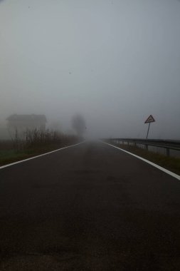 Sonbaharda sisli bir günde bir su akıntısı ile çevrili köy yolu