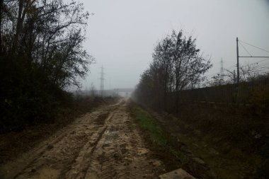 İtalya kırsalında sisli bir günde tren yolunun yanındaki çamurlu yolda.