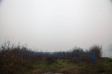 Kışın sisli bir günde mavi bir çubuğu olan ekilmemiş tarla.