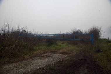 Kışın sisli bir günde mavi bir çubuğu olan ekilmemiş tarla.