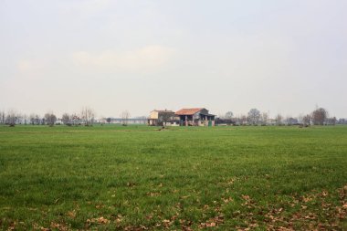 Country house in the fields seen from afar on a cloudy day in the italian countryside