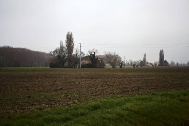Country house in a field surrounded by trees on a cloudy day in the italian countryside