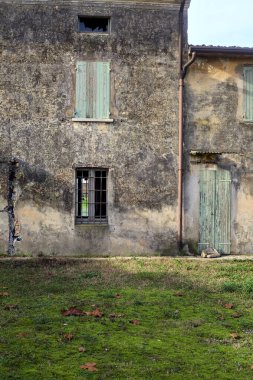 Facade of an abandoned country house with a wooden door on a cloudy day