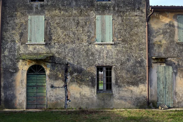 Facade of an abandoned country house with a wooden door on a cloudy day