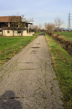 Abandoned country house by the edge of a paved trail in the italian countryside
