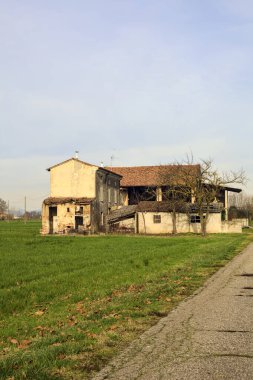 Abandoned country house by the edge of a paved trail in the italian countryside