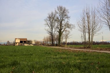 Abandoned country house by the edge of a paved trail in the italian countryside