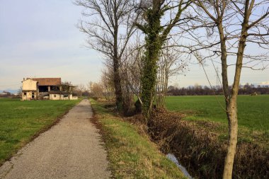 Abandoned country house by the edge of a paved trail in the italian countryside