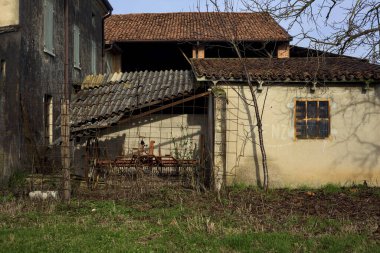 Two bare trees next to an abandoned country house in a field