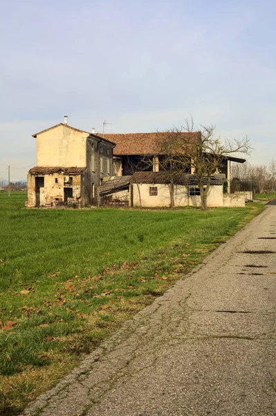 Abandoned country house by the edge of a paved trail in the italian countryside