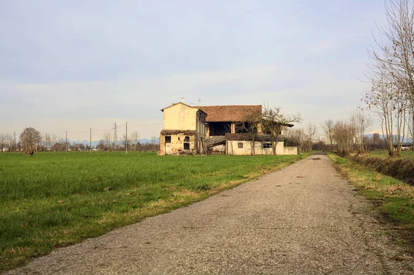 Abandoned country house by the edge of a paved trail in the italian countryside