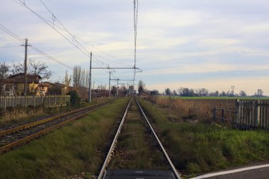 Railroad crossing next to a field on a cloudy day in the italian countryside