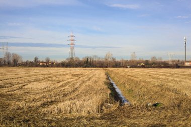 Rows of electricity pylons and power lines over cultivated fields on a winter day in the italian countryside
