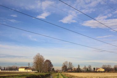 Path between cultivated fields and bordered by streams of water in the italian countryside