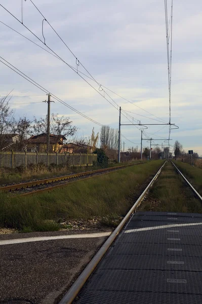 Railroad crossing next to a field on a cloudy day in the italian countryside