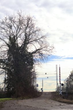 Trail bordered by a stream of water with a railroad crossing over an embankment in the italian countryside