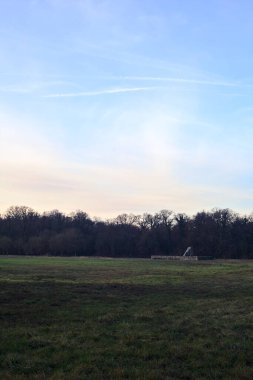 Günbatımında İtalya kırsalında bir ormanın yanındaki çayırda bir manastırın kalıntıları.