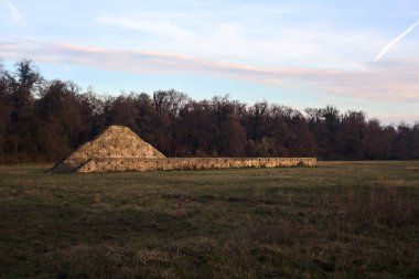Günbatımında İtalya kırsalında bir ormanın yanındaki çayırda bir manastırın kalıntıları.