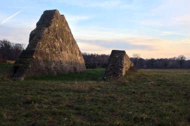 Günbatımında İtalya kırsalında bir ormanın yanındaki çayırda bir manastırın kalıntıları.