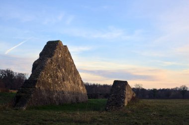 Günbatımında İtalya kırsalında bir ormanın yanındaki çayırda bir manastırın kalıntıları.