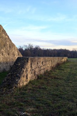 Günbatımında İtalya kırsalında bir ormanın yanındaki çayırda bir manastırın kalıntıları.