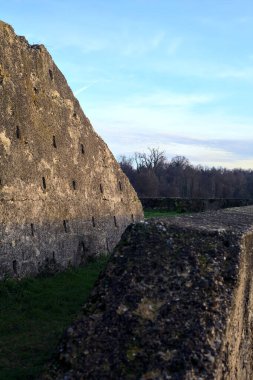 Günbatımında İtalya kırsalında bir ormanın yanındaki çayırda bir manastırın kalıntıları.