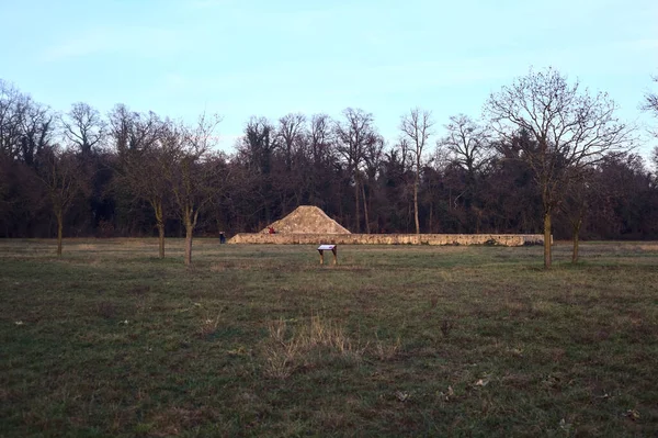 Günbatımında İtalya kırsalında bir ormanın yanındaki çayırda bir manastırın kalıntıları.