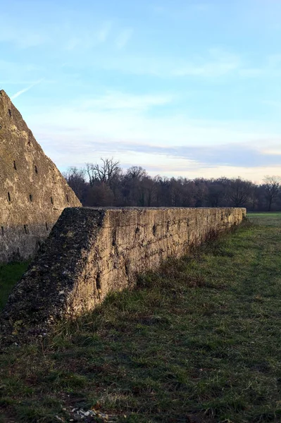 Günbatımında İtalya kırsalında bir ormanın yanındaki çayırda bir manastırın kalıntıları.