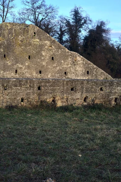 Günbatımında İtalya kırsalında bir ormanın yanındaki çayırda bir manastırın kalıntıları.
