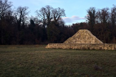 Günbatımında İtalya kırsalında bir ormanın yanındaki çayırda bir manastırın kalıntıları.