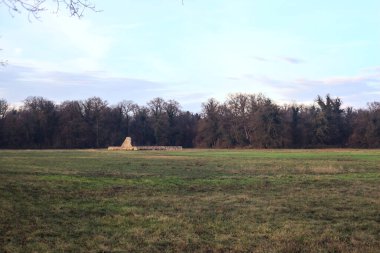 Günbatımında İtalya kırsalında bir ormanın yanındaki çayırda bir manastırın kalıntıları.