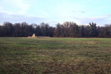 Günbatımında İtalya kırsalında bir ormanın yanındaki çayırda bir manastırın kalıntıları.