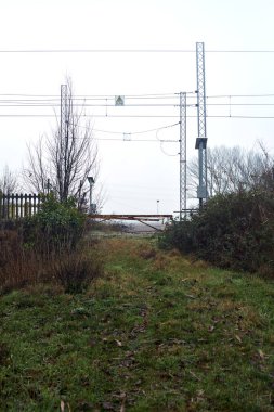 Railroad crossing with rusty bars blocking it on a cloudy day in the italian countryside in winter