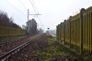 Railroad on an embankment bordered by trees on a misty day in winter