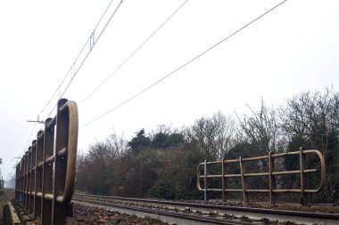 Railroad on an embankment bordered by trees on a misty day in winter