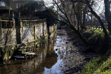 Staircase of a group of houses by the edge of a stream of water on a sunny day in the italian countryside