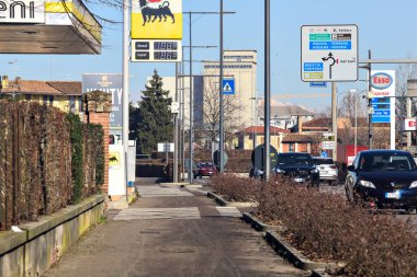 Country road with gas stations and cars passing by on a sunny day