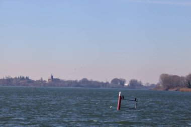 Buoy on a lake with a forest on the horizon on a sunny and windy day