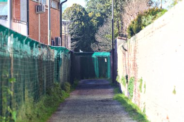 Path between a fence and a brick wall in a rural town