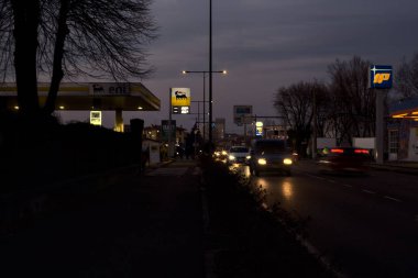 Road at dusk with cars passing by and gas stations at its edge