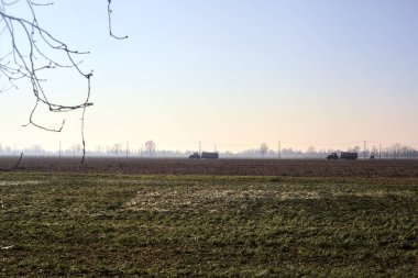 Tractors with tanks on a country road between fields on a sunny day in winter