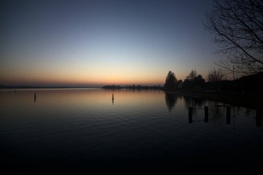 Lake at sunset with trees and the sky casted in the water