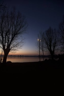 Street lamp by the lakeshore in a park at sunset