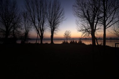 Lake at sunset with trees and the sky casted in the water