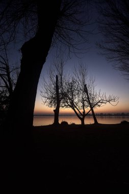 Lake at sunset with trees and the sky casted in the water