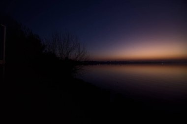 Lake at sunset with trees and the sky casted in the water