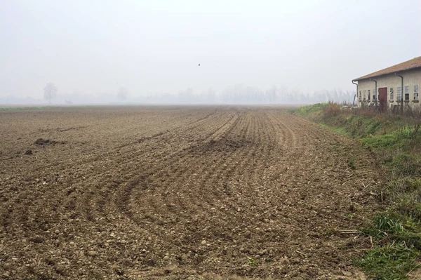 stock image Ploughed field and a barn next to it on a foggy day in the italian countryside